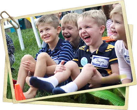 A row of children sitting on the grass, laughing hysterically at the Jungle Jimmy show