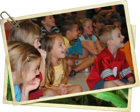 Young children leaning forward, wide-eyed and grinning at the magic