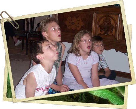 Four children sitting on a living room floor, mouths open in amazement